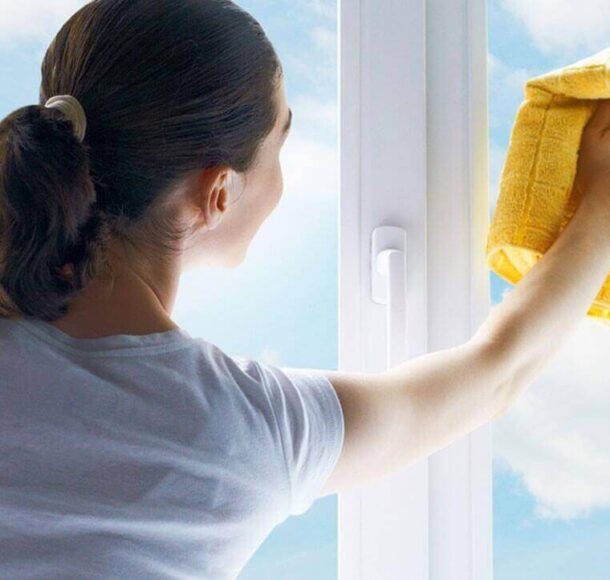 A woman from office cleaning services is wiping the window pane